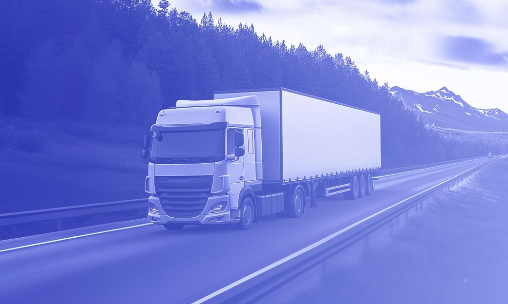 White cargo truck driving on highway through mountains