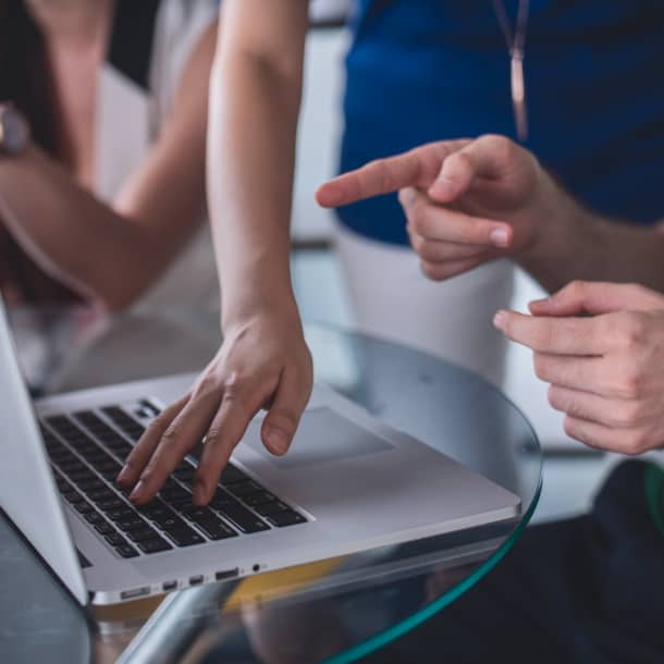 People discussing a topic next to a MacBook