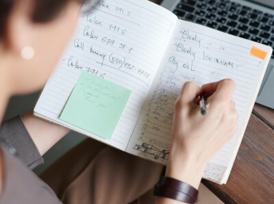 A person makes notes with a pen in a notebook