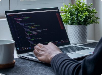  A person in a dark sweater writing code on a laptop