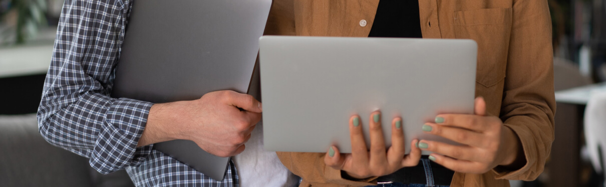 Two people in shirts holding two laptops