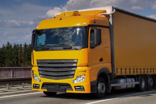 A yellow truck transports goods on a highway