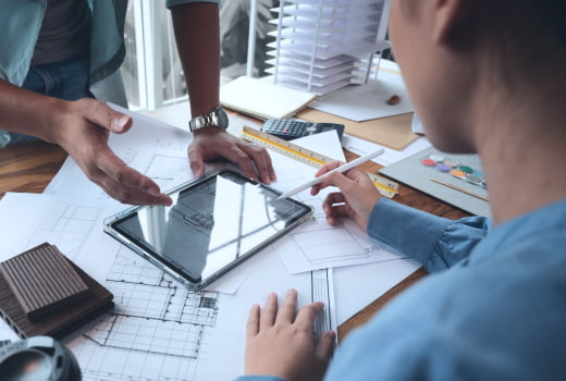 Architectures discussing the building plan displayed on a tablet