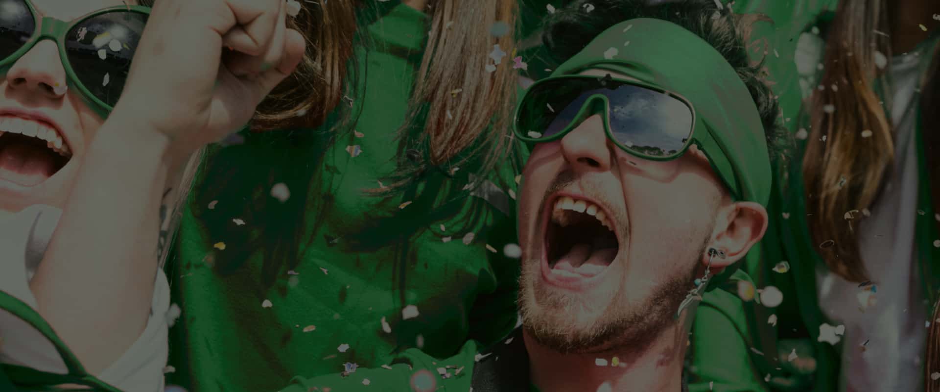 Football fans in green uniform celebrating a goal