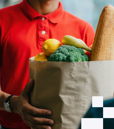 A person in a red t-shirt carrying a grocery store bag