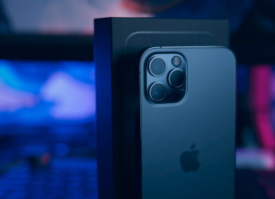 A grey iPhone standing on a table next to its box