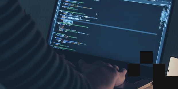 A person writes code of a program on a laptop