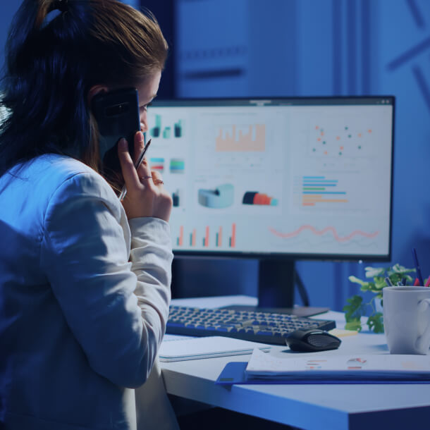 A person talking on a phone in front of a monitor